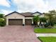Attractive home with a brick driveway, neatly manicured lawn, and a convenient three-car garage at 13634 Vancanza Dr, Venice, FL 34293