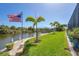 Backyard features lush lawn, mature palms, dock, boat lift, and canal access with an American flag at 14398 Fort Worth Cir, Port Charlotte, FL 33981
