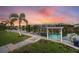 Beautiful backyard with a private dock, swing, and waterway view at sunset, surrounded by lush landscaping at 14398 Fort Worth Cir, Port Charlotte, FL 33981