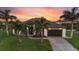 Beautiful home with tropical landscaping, an attached garage, and a lush green lawn at sunset at 14398 Fort Worth Cir, Port Charlotte, FL 33981