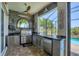 A covered outdoor kitchen featuring stainless steel appliances, a stone backsplash and a view of the pool and canal at 14398 Fort Worth Cir, Port Charlotte, FL 33981