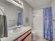 Bright bathroom with a white vanity, framed mirror, white-tiled shower, and sea-themed shower curtain at 1531 Placida Rd # 202 Building 9, Englewood, FL 34223