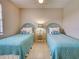 Bright bedroom with two twin beds, floral pillows, tile floors, and neutral walls illuminated by a ceiling fan at 1531 Placida Rd # 202 Building 9, Englewood, FL 34223