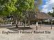 View of the Englewood Farmers' Market site featuring a thatched roof picnic shelter under a canopy of trees at 1531 Placida Rd # 202 Building 9, Englewood, FL 34223