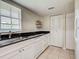Bright kitchen featuring white cabinets, black countertops, stainless steel sink, and tiled floor at 1531 Placida Rd # 202 Building 9, Englewood, FL 34223