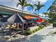 Outdoor patio seating area with colorful umbrellas, tables and chairs on a paved walkway at 1531 Placida Rd # 202 Building 9, Englewood, FL 34223