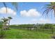 Enjoy beautiful backyard views from this yard surrounded by an iron fence, green grass, and mature palm trees at 15336 Spanish Point Dr, Port Charlotte, FL 33981