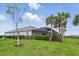 A sprawling backyard with lush green grass, a screened-in lanai, and views of towering palm trees at 15336 Spanish Point Dr, Port Charlotte, FL 33981