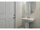 A charming half bathroom featuring a pedestal sink, an oval mirror, and a door to the exterior of the home at 15336 Spanish Point Dr, Port Charlotte, FL 33981