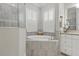 Bright bathroom featuring a soaking tub with gray tiled walls and white plantation shutters at 15336 Spanish Point Dr, Port Charlotte, FL 33981