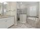 Bright bathroom featuring a soaking tub and glass enclosed shower with white vanity at 15336 Spanish Point Dr, Port Charlotte, FL 33981