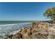 Scenic beach view with gentle waves, rocky shoreline, and clear blue skies at 1555 Tarpon Center Dr # G 235, Venice, FL 34285