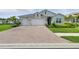 Charming single-Gathering home featuring a brick driveway, a two-car garage, and a well-manicured lawn with mature landscaping at 15963 Crofton Springs Way, Port Charlotte, FL 33953