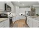 Modern kitchen with white cabinets, stainless steel appliances, marble countertops, and hardwood floors throughout at 15963 Crofton Springs Way, Port Charlotte, FL 33953