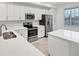 Well-lit kitchen features stainless steel appliances, white cabinetry, quartz countertop and island seating at 17595 Opal Sand Dr # 205, Venice, FL 34293