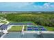 Aerial view of multiple community pickleball courts surrounded by green space, trees and residential buildings at 17595 Opal Sand Dr # 205, Venice, FL 34293