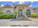 Home's entrance features a covered porch, decorative columns, and beautiful landscaping at 188 Grand Oak Cir, Venice, FL 34292