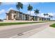Inviting exterior view of multi-Gathering residence and palm trees with well-manicured lawn and street at 200 The Esplanade N # C19, Venice, FL 34285