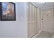 Hallway shot featuring a closet with bi-fold doors, a front door, neutral paint, and art at 200 The Esplanade N # C19, Venice, FL 34285