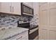 Cozy kitchen featuring stainless steel appliances, granite countertops, and stylish backsplash and hardware at 200 The Esplanade N # C19, Venice, FL 34285