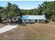 Charming single-story home with a white metal roof, surrounded by mature trees and a gravel driveway at 2008 55Th E Ave, Bradenton, FL 34203