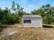 A small white storage shed with a window and dark shutters sits amid the trees in the backyard at 2008 55Th E Ave, Bradenton, FL 34203