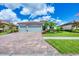 Lovely one-story home with three-car garage, a brick driveway, manicured lawn, and attractive landscaping at 20235 Granlago Dr, Venice, FL 34293