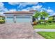 A beautifully landscaped one-story home boasting a brick driveway, stone accents, and a three-car garage at 20235 Granlago Dr, Venice, FL 34293