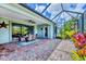 Screened lanai features brick pavers, dining table, ceiling fan, and access to lush tropical landscaping at 20235 Granlago Dr, Venice, FL 34293