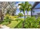 Landscaped backyard with tropical palms overlooking a serene lake at 213 Malina Ct, Nokomis, FL 34275