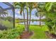 Lush backyard with tropical palms overlooking a tranquil lake at 213 Malina Ct, Nokomis, FL 34275