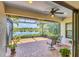 Covered patio with peaceful lake views, featuring a ceiling fan and ample space for outdoor furniture and relaxation at 213 Malina Ct, Nokomis, FL 34275