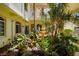 Exterior courtyard with vibrant tropical landscaping and decorative water feature at 235 Base E Ave # 207, Venice, FL 34285
