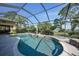 A screened-in pool with tropical landscaping, a view of the lake, and outdoor furniture at 249 Hallcrest Ter, Port Charlotte, FL 33954
