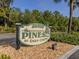 The PINES at Deep Creek community sign is surrounded by manicured landscaping and a bed of decorative pebbles at 25050 Sandhill Blvd # 6A3, Punta Gorda, FL 33983