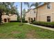 Townhouse featuring lush landscaping, lawn, and mature palm trees at 3613 Parkridge Cir # 11-201, Sarasota, FL 34243