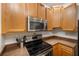 Kitchen showcasing black appliances, hardwood cabinets, and modern microwave at 3613 Parkridge Cir # 11-201, Sarasota, FL 34243