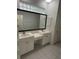 Bathroom with dual sinks, white cabinetry, and a large framed mirror, offering a clean aesthetic at 3790 Cadbury Cir # 40, Venice, FL 34293