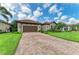 Paver driveway leading to a home with lush landscaping and a brown two-car garage at 4740 Royal Dornoch Cir, Bradenton, FL 34211