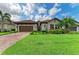 Charming home with a well-manicured lawn, lush landscaping, and a brown two-car garage at 4740 Royal Dornoch Cir, Bradenton, FL 34211