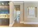 Hallway with hardwood floors leading to the bedroom and bar area with granite counters and wooden cabinets at 4740 Royal Dornoch Cir, Bradenton, FL 34211