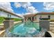 Backyard swimming pool with fountain features, surrounded by lush landscaping and a blue sky at 4740 Royal Dornoch Cir, Bradenton, FL 34211