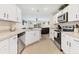 Bright kitchen featuring white cabinets, stainless steel appliances, and a view of the living room at 4890 Laramie Cir, North Port, FL 34286