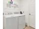 Functional laundry room with white washer and dryer units, shelving, and a white door at 4890 Laramie Cir, North Port, FL 34286