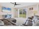 Cozy living room featuring a leather sofa, sliding glass doors to the backyard, and a ceiling fan at 4890 Laramie Cir, North Port, FL 34286