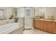 Bright bathroom featuring a garden tub, glass-enclosed shower, and vanity with a marble countertop at 5018 Bella Terra Dr, Venice, FL 34293