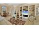 Open-concept living room boasts built-in shelves and decorative glass table on marble flooring at 5018 Bella Terra Dr, Venice, FL 34293