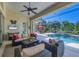 Inviting covered patio with comfortable seating, ceiling fan, and view of the sparkling pool at 5018 Bella Terra Dr, Venice, FL 34293