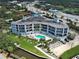 Aerial view of condo building featuring balconies, pool, landscaping, and waterfront location; balcony unit highlighted at 516 Tamiami S Trl # 303, Nokomis, FL 34275