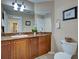 Bathroom featuring wood cabinetry with stone counters, toilet, and decorative wall art at 516 Tamiami S Trl # 303, Nokomis, FL 34275